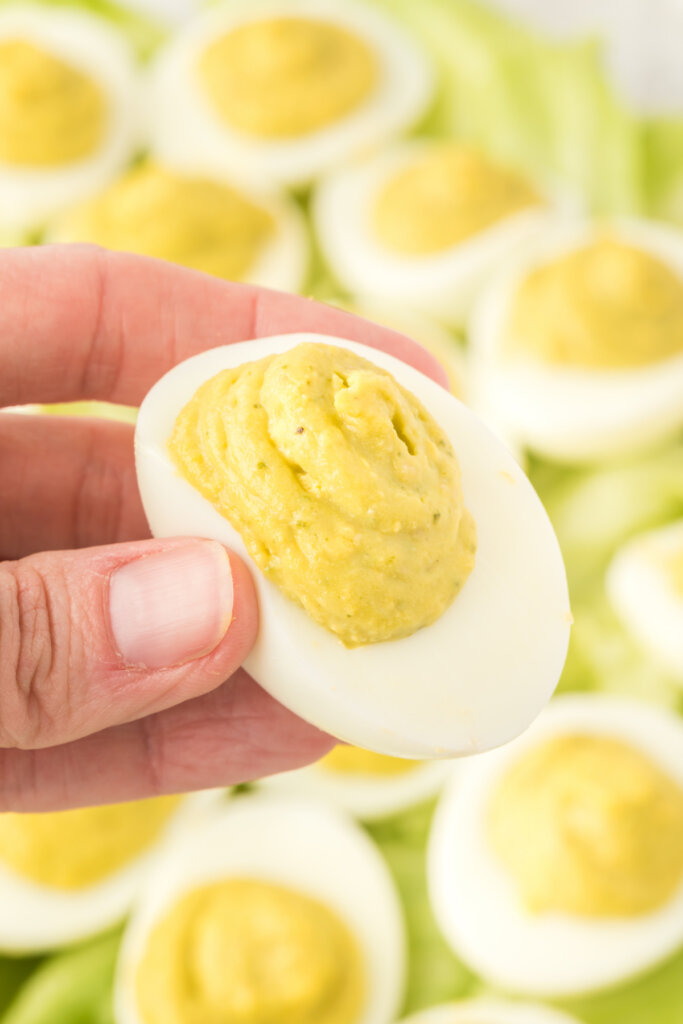 hand holding a pesto deviled egg over other pest deviled eggs