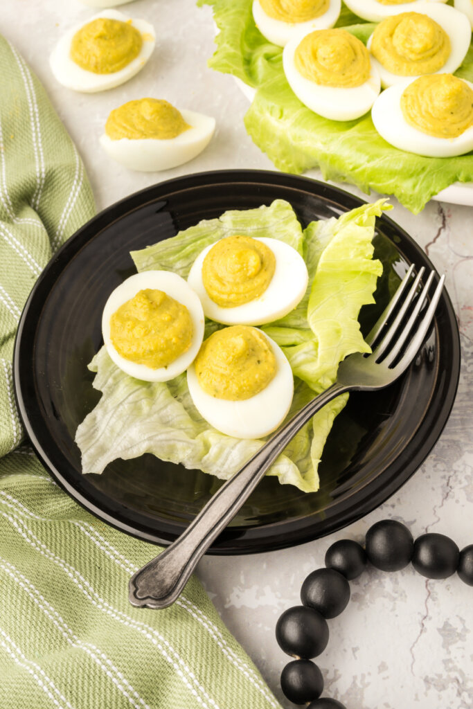 three pesto deviled eggs on black plate