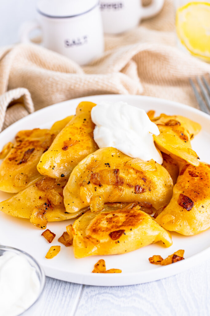 cooked pierogi on plate with onions and sour cream