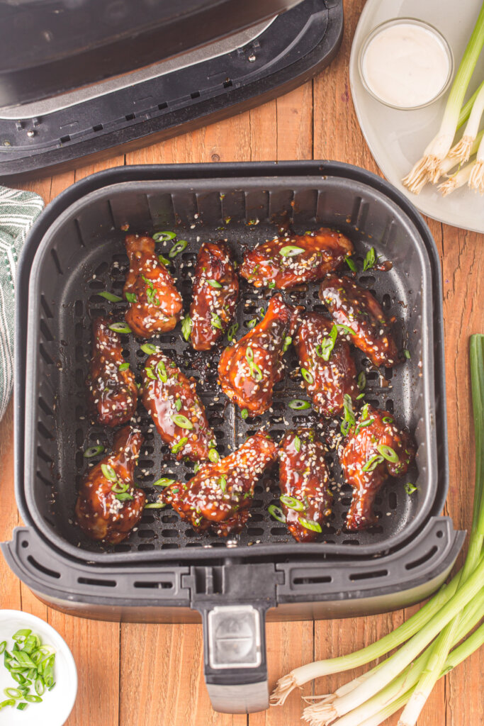 air fryer basket with teriyaki chicken wings in it