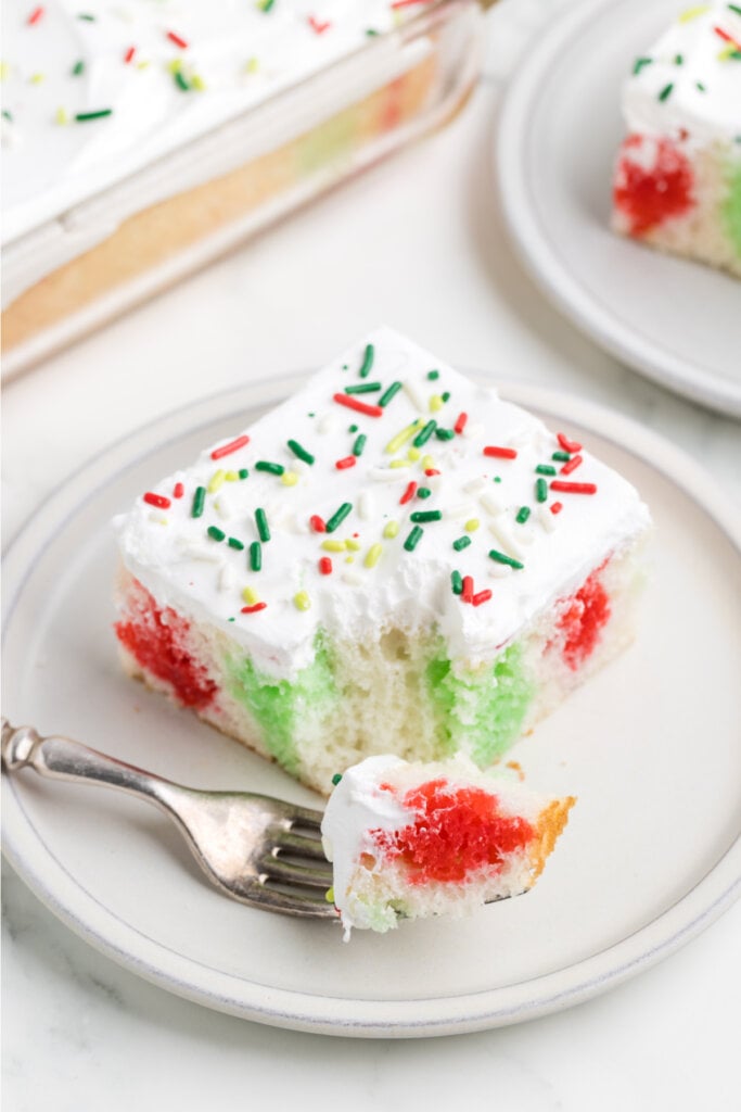 slice of christmas poke cake with bite on spoon laying on plate