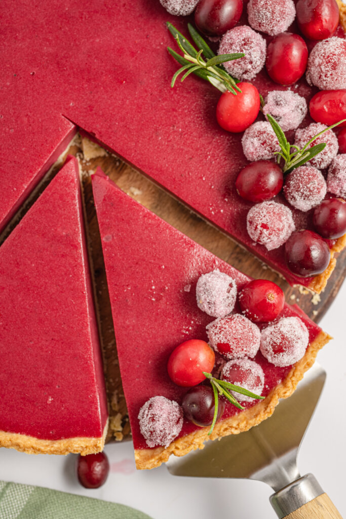 a slice of cranberry tart being removed from the whole pie