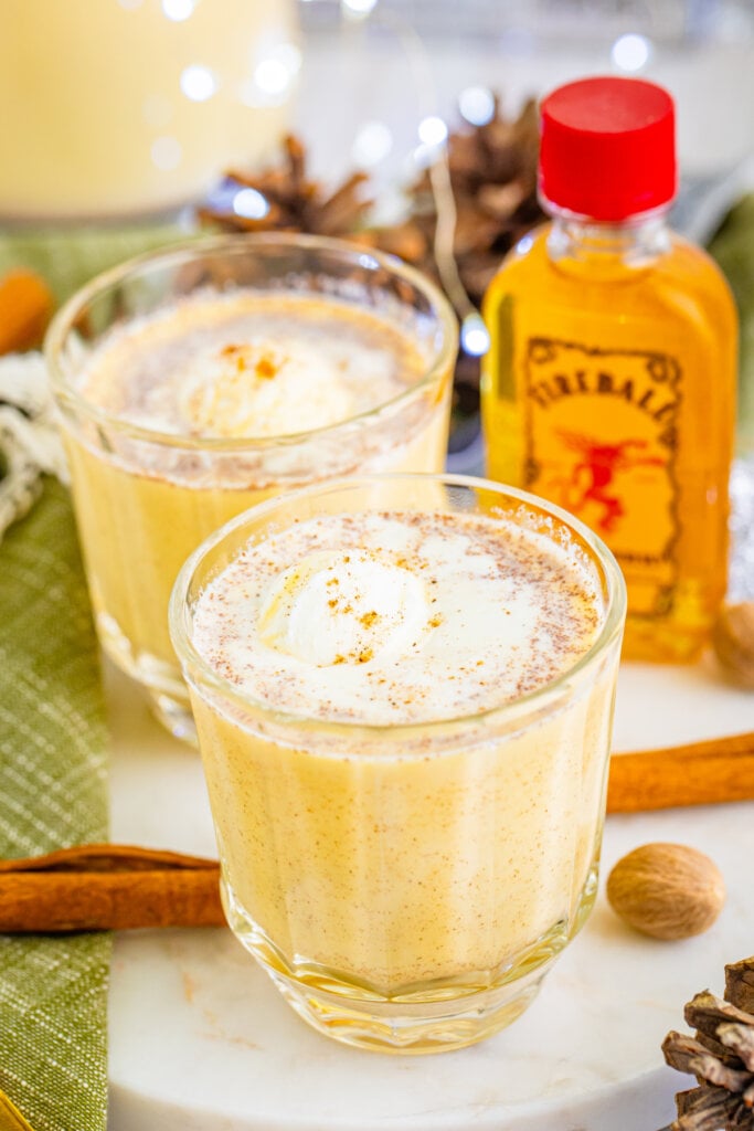 fireball whiskey bottle and two glasses of eggnog punch