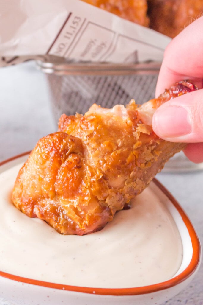 hand dipping a chicken wing into sauce