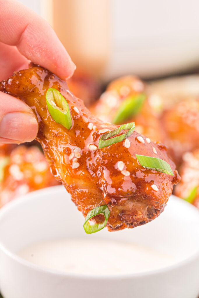 hand getting ready to dip honey sriracha wings in dip