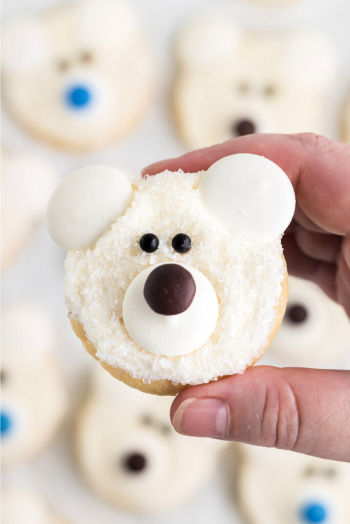 hand holding a decorated polar bear face cookie