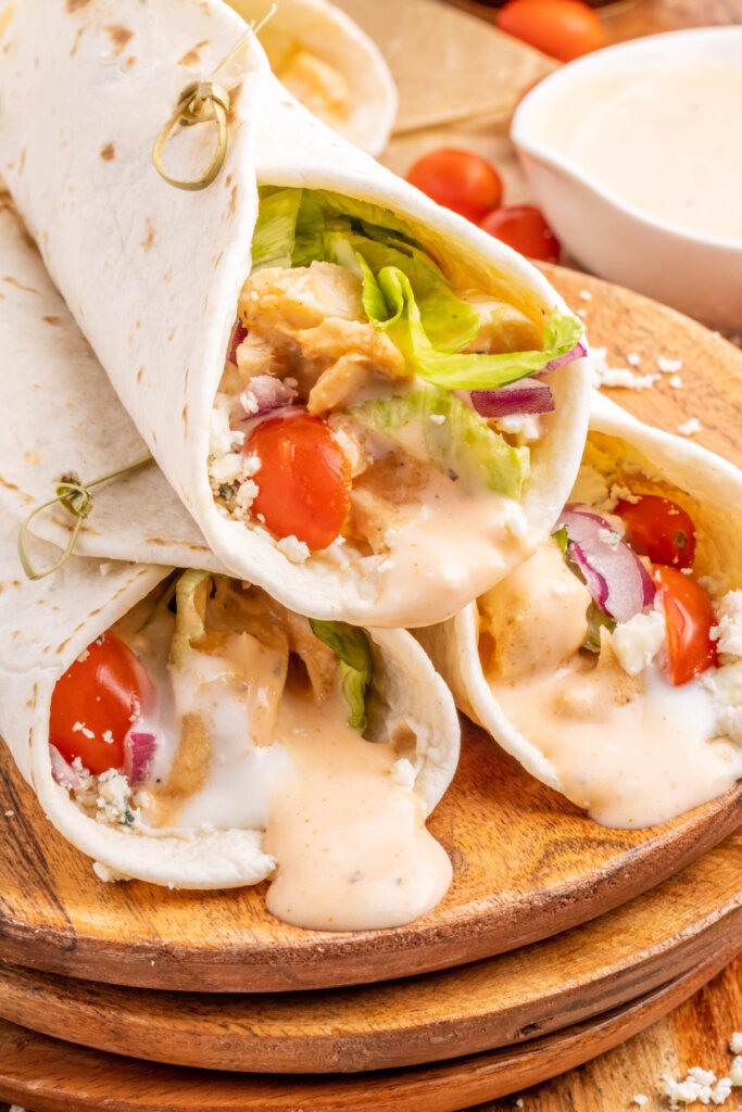 three buffalo chicken wraps on cutting board