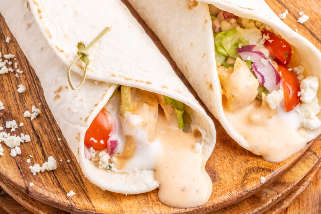 two buffalo chicken wraps on wooden cutting board