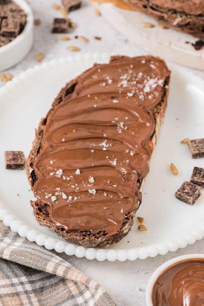 slice of chocolate no knead bread spread with nutella and sprinkled with salt on plate