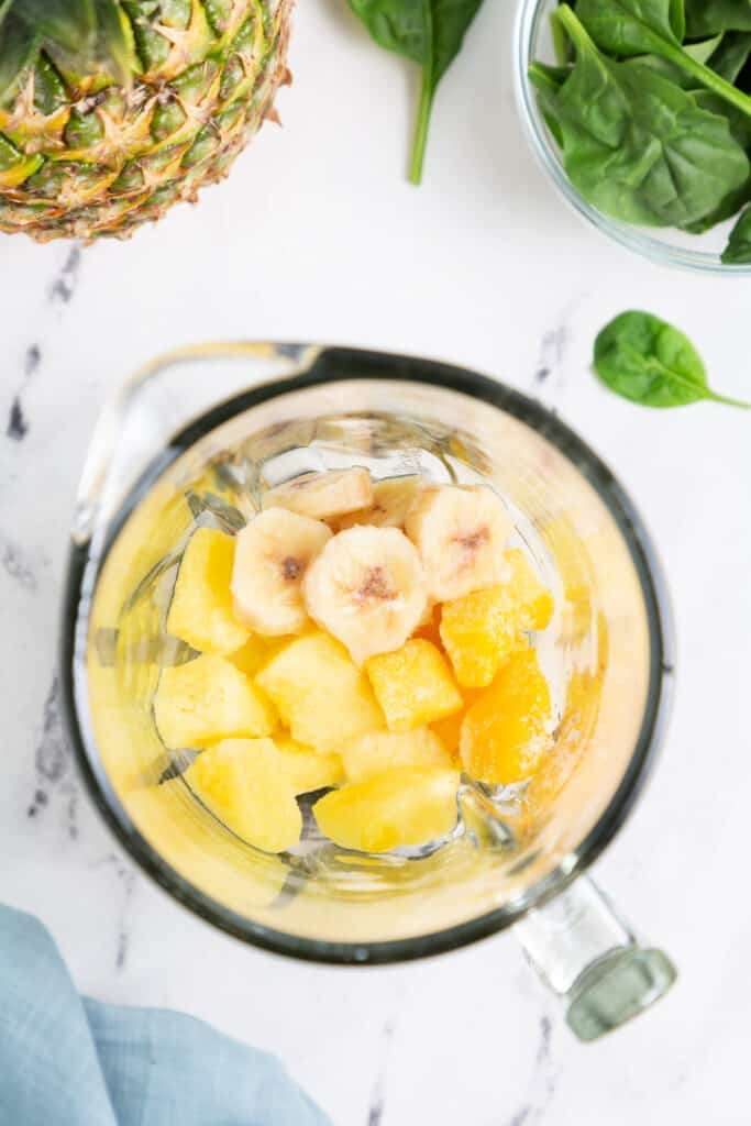 Add the frozen pineapple, mango, and banana to the blender. 