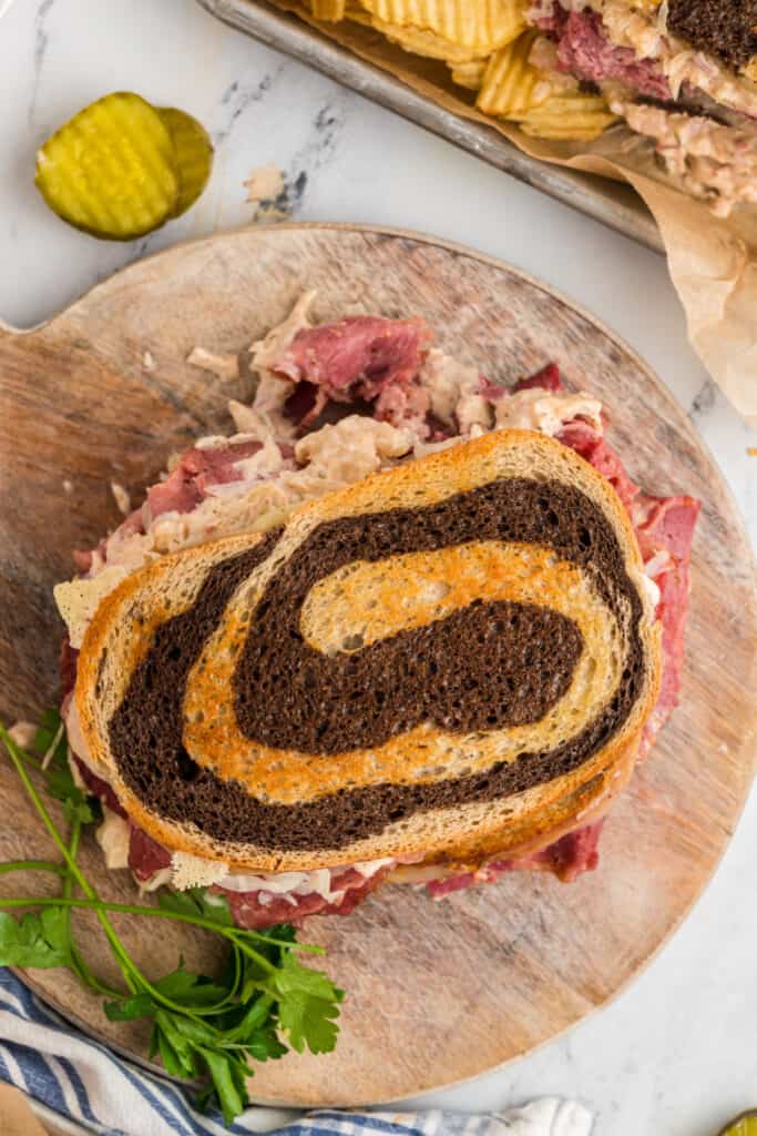 looking down onto a whole reuben sandwich on a wooden cutting board