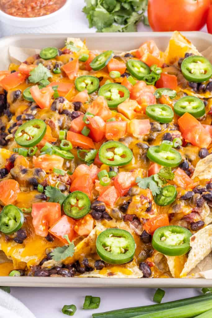 closeup of spicy loaded black bean nachos on sheet pan