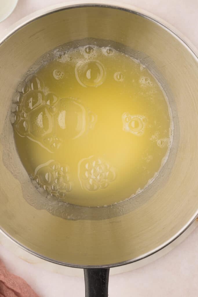 Fill a saucepan with a couple of inches of water and bring it to a simmer. Put the egg whites and sugar into the bowl of a stand mixer and set it over the simmering pan. Do not let the bottom of the bowl touch the water, or the egg whites will scramble.