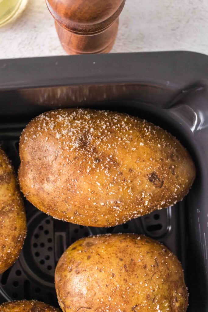 oiled and seasoned potatoes in an air fryer basket