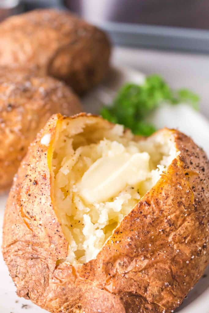 closeup of an air fryer baked potato split open with butter inside