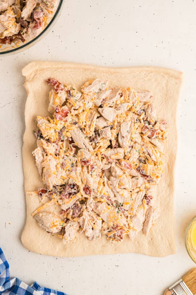 On a clean work surface, lay out pizza dough in rectangles. Spread half of the chicken mixture onto each dough, leaving a 1” border along the edges.