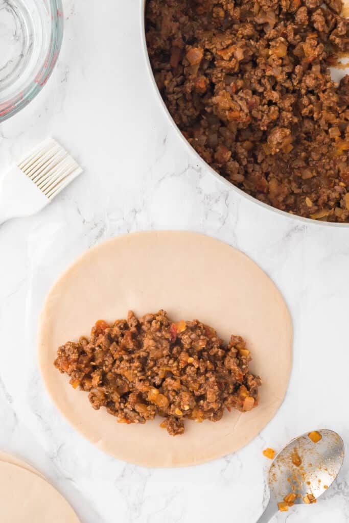 Preheat the air fryer to 350°F (190°C). Lay out the empanada discs on a clean surface. Place 2-3 tablespoons of the beef mixture in the center of each disc.