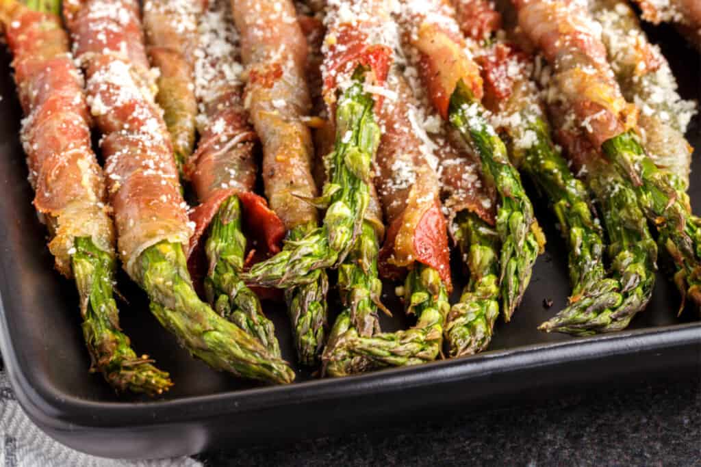 air fryer prosciutto wrapped asparagus on black plate