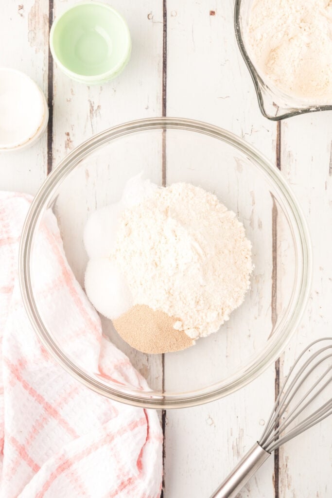 In a large bowl, whisk together 2 cups flour, yeast, sugar, salt, and baking soda.