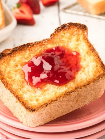 closeup of toasted english muffin bread with jam on pink plates