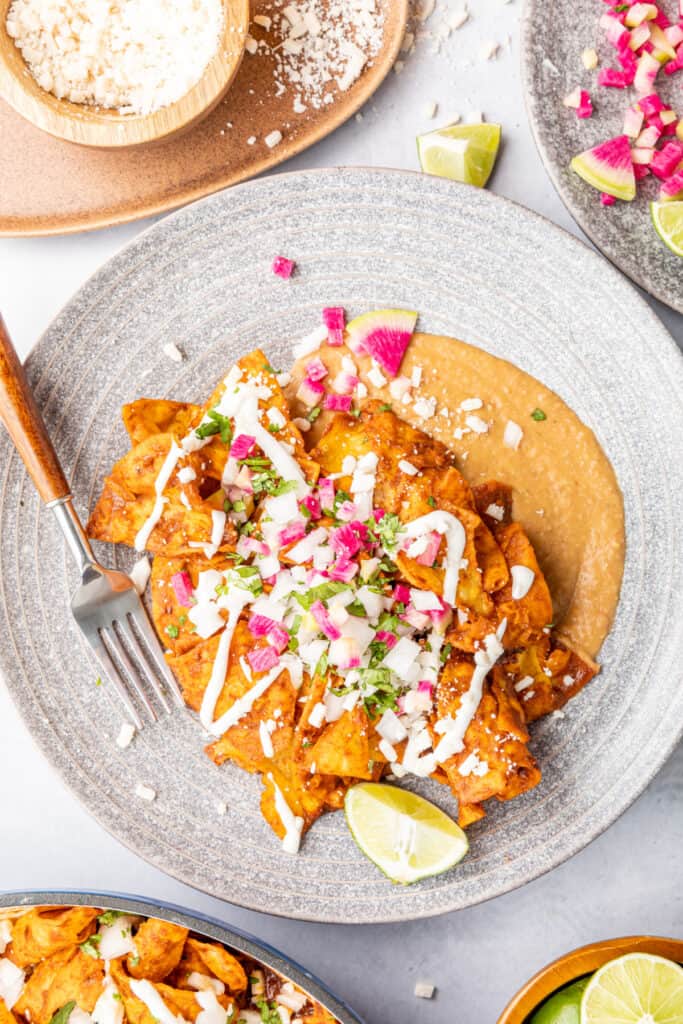 portion of mole chilaquiles on plate with refried beans