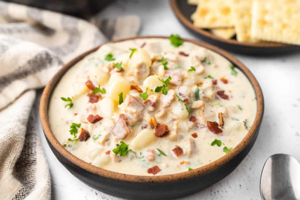 bowl of new england clam chowder garnished with bacon
