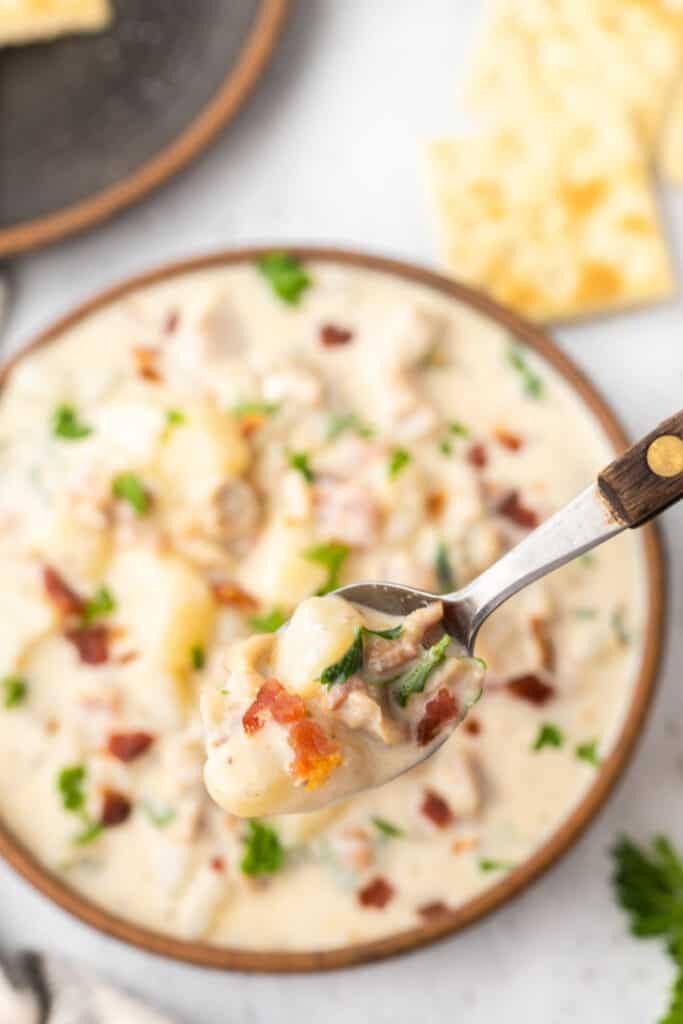 spoon holding a bite of clam chowder of a bowl