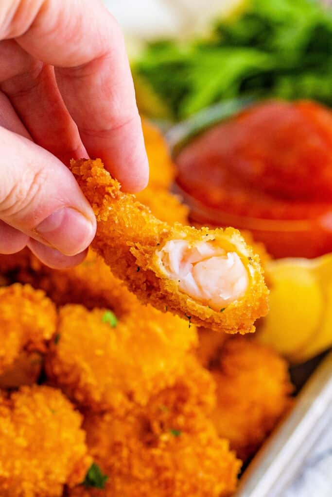 a panko fried shrimp with a bite taken out to show the inside