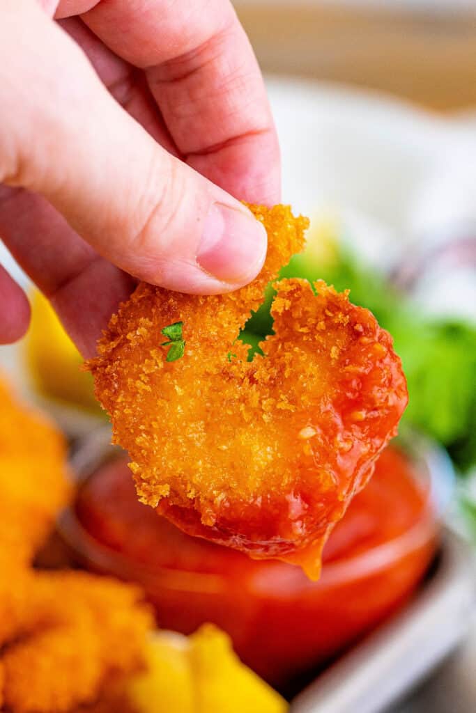 hand holding a panko fried shrimp dipped in shrimp cocktail sauce