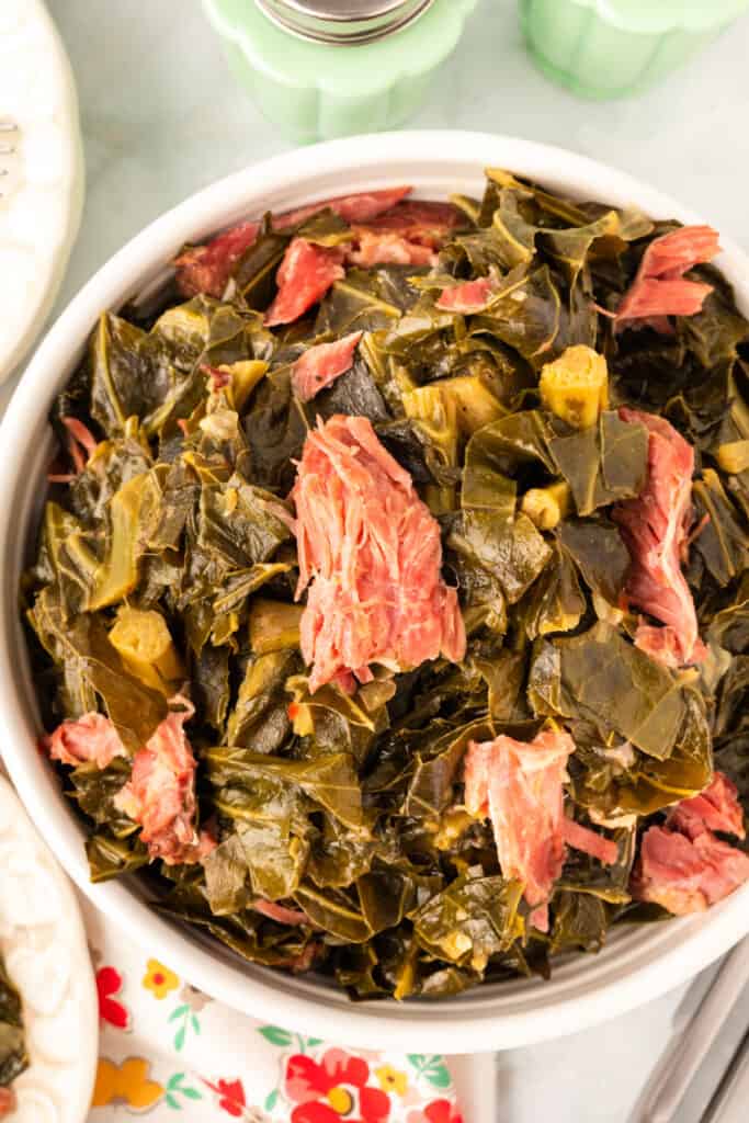closeup of cooked southern style collard green with ham hocks in a bowl