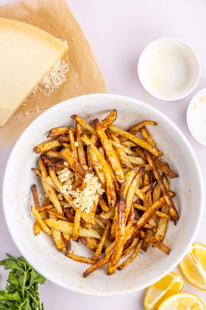 While the potatoes are in their final 2 minutes of cooking add the melted butter and garlic to the large bowl. Remove the potatoes from the air fryer and place them back into the bowl with the garlic and melted butter. Toss the fries in the garlic butter and the leftover seasonings in the bowl. Place the fries back in the air fryer and cook for an additional 3-5 minutes if you want them crispier. 