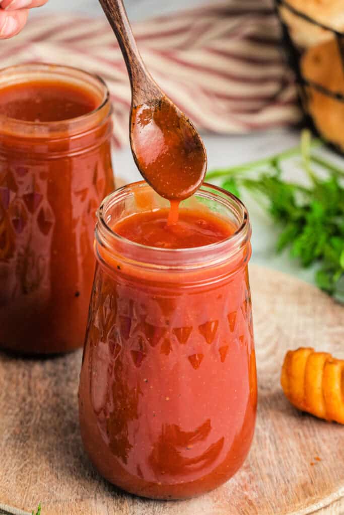 copycat arby's sauce on spoon over glass jar holding sauce