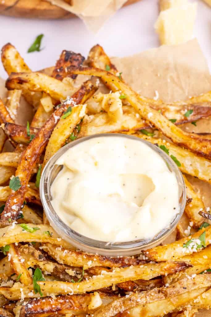 garlic aioli in small glass bowl with homemade fries around the bowl