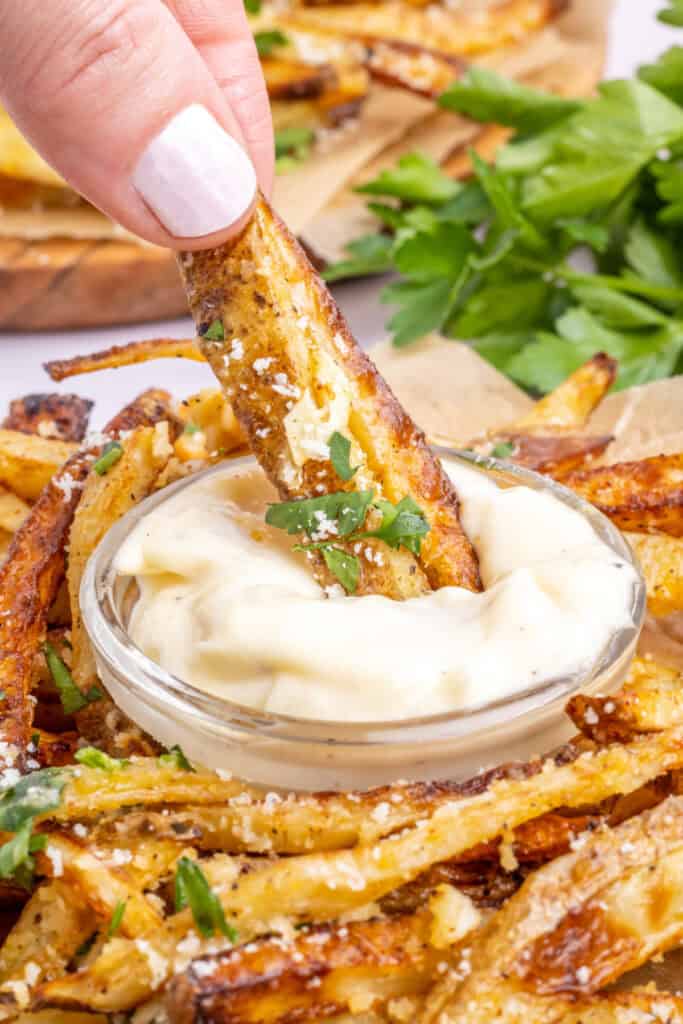 fries being dipped into garlic aioli