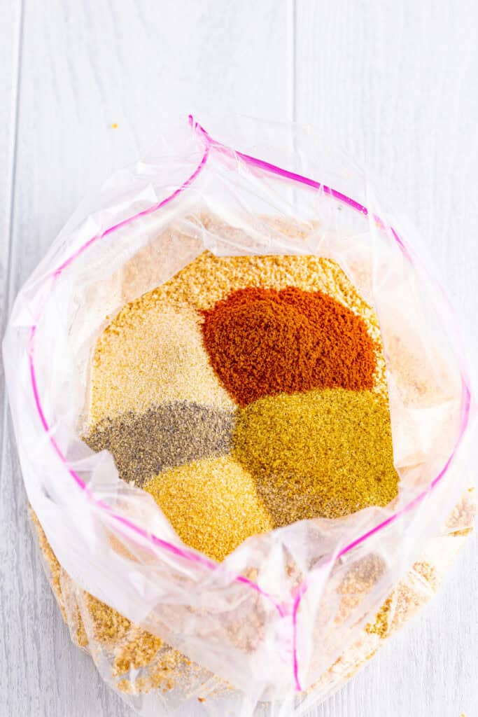 Preheat your oven to 425°F. Line a baking sheet with parchment paper. In a gallon-sized zip-top bag, combine breadcrumbs, seasoned salt, paprika, black pepper, celery salt, garlic powder, and onion powder. 
