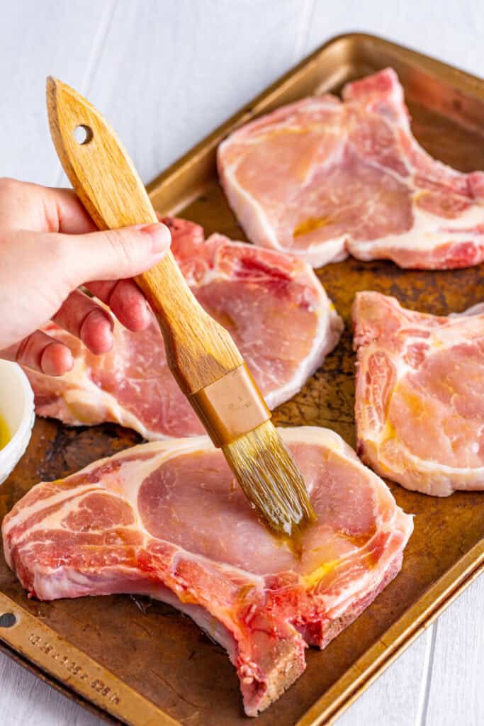Brush the pork chops with olive oil, ensuring they are well coated.