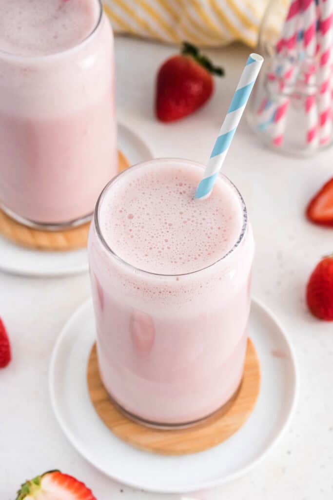 glass of strawberry milk with a blue and white straw