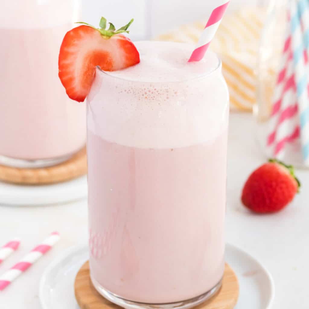 closeup of a glass of strawberry milk garnished with a fresh strawberry