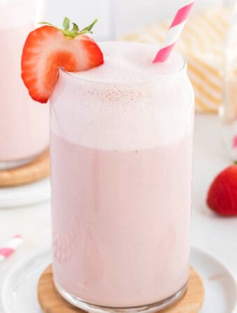 closeup of a glass of strawberry milk garnished with a fresh strawberry