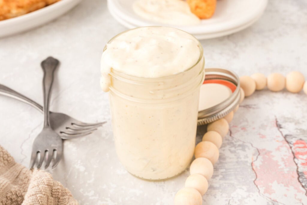 tartar sauce in a glass jar with crisscrossed forks and decorative beads near by