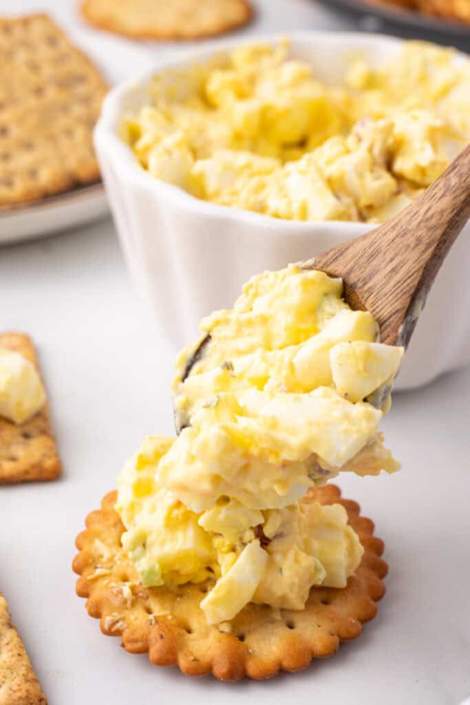 spoon putting million dollar egg salad onto a cracker