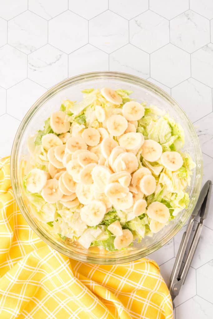 thin sliced bananas on top of lettuce ready to be mixed in