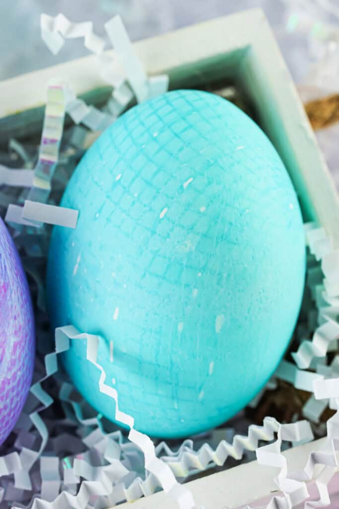 closeup of a teal fabric textured easter egg in a wooden box