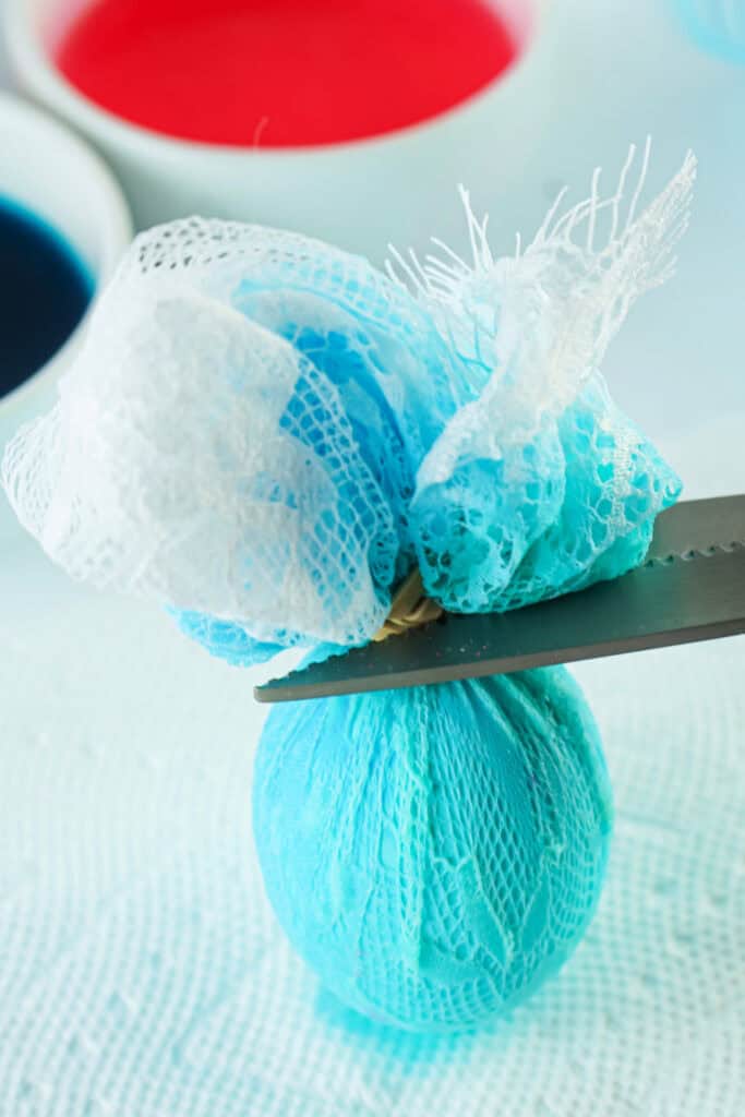 cutting the rubber band and lace off the dyed easter egg
