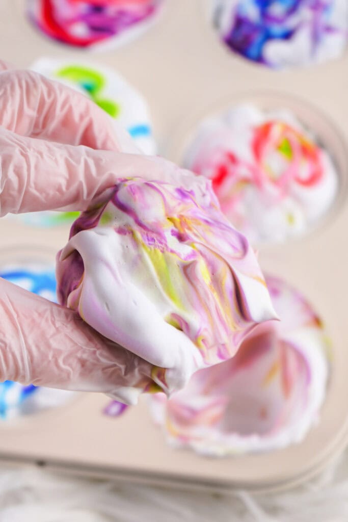 hand holding a colored shaving cream covered egg