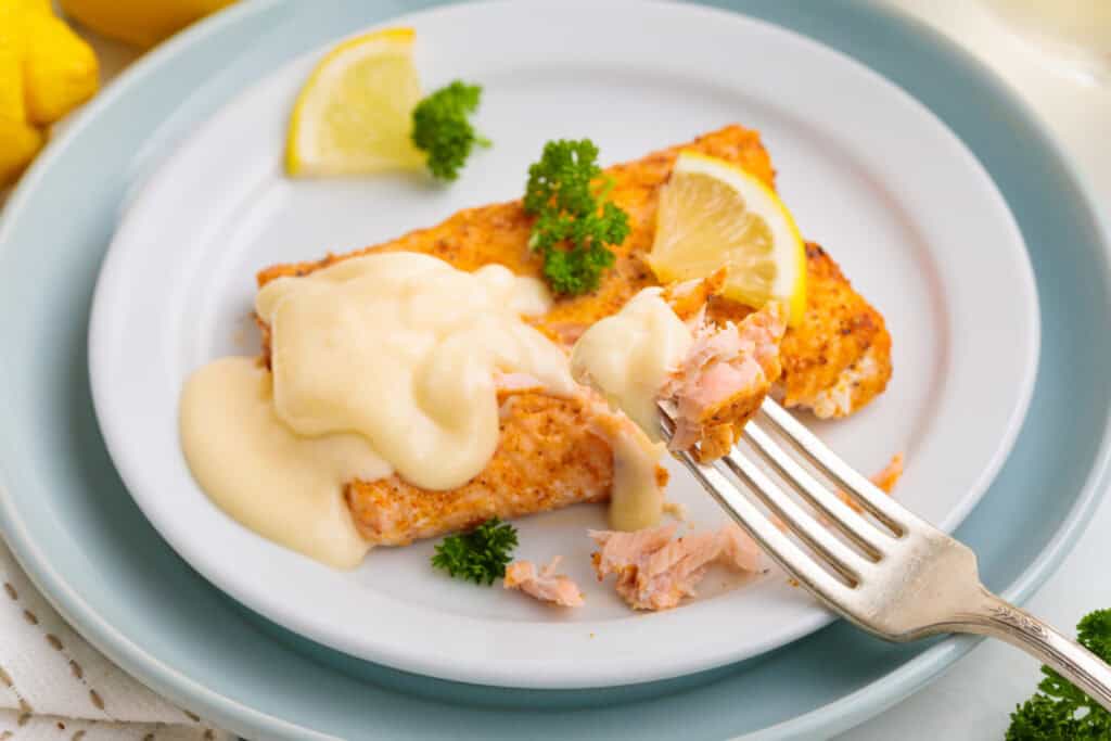 air fryer frozen salmon topped with lemon butter sauce, parsley sprig, and lemon pieces