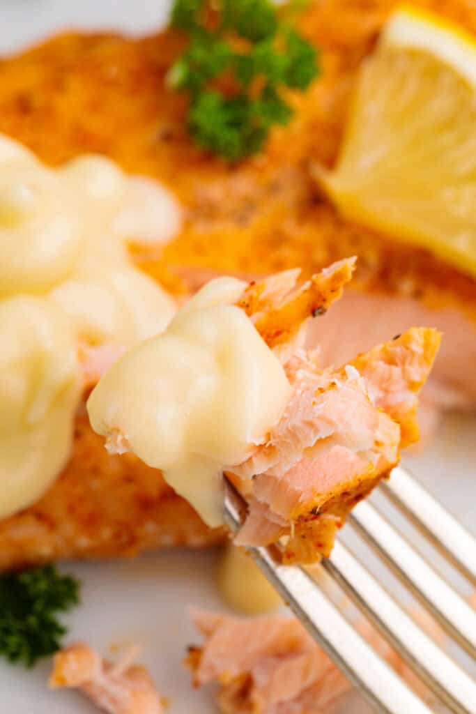 closeup of a bite of salmon on a fork with lemon butter sauce