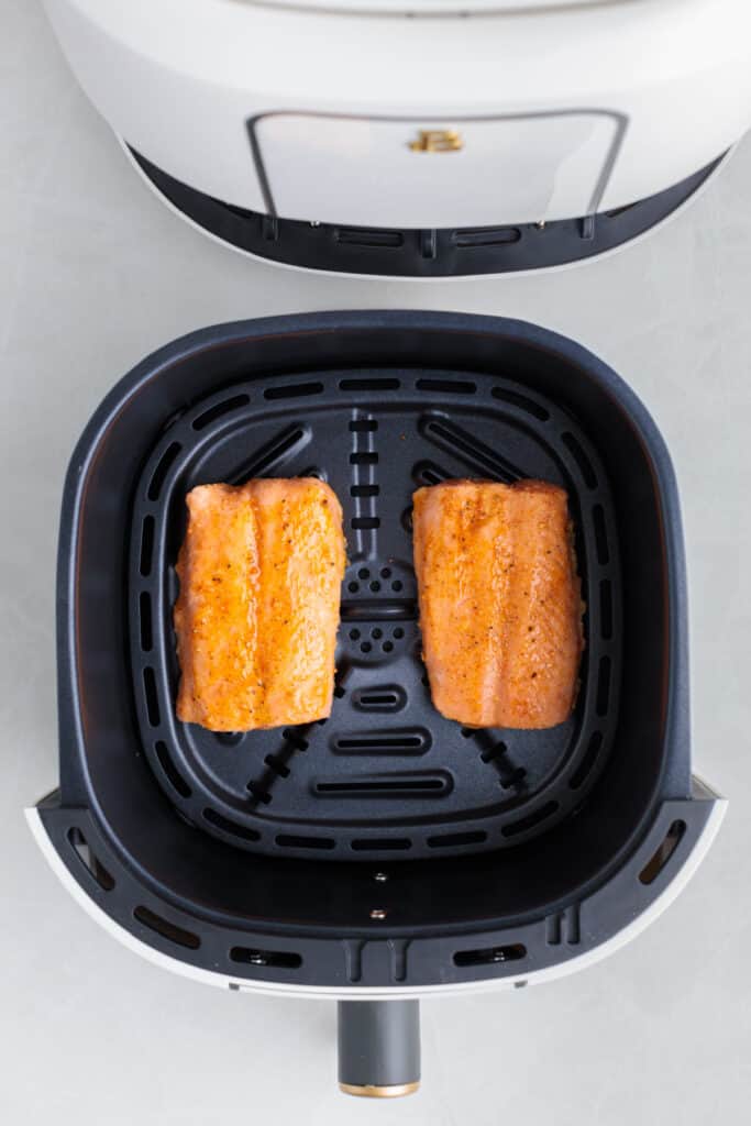 two pieces of salmon in the air fryer basket