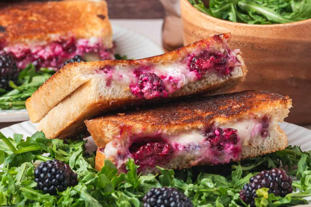 Close-up of stacked grilled cheese sandwiches with blackberry filling and melted cheese