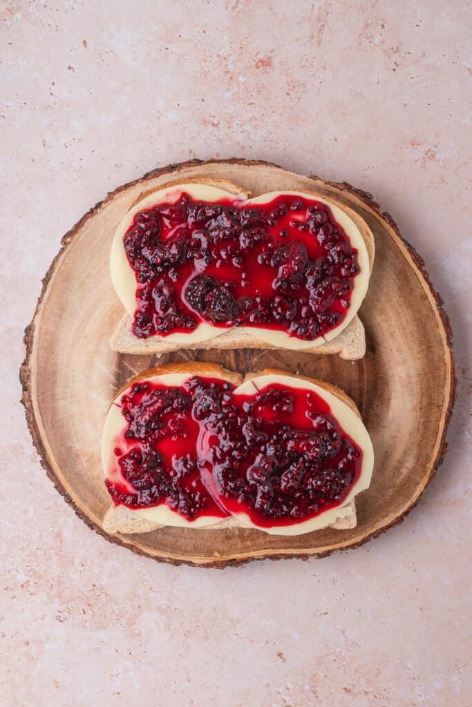 Provolone-topped bread slices covered with a layer of blackberry jam